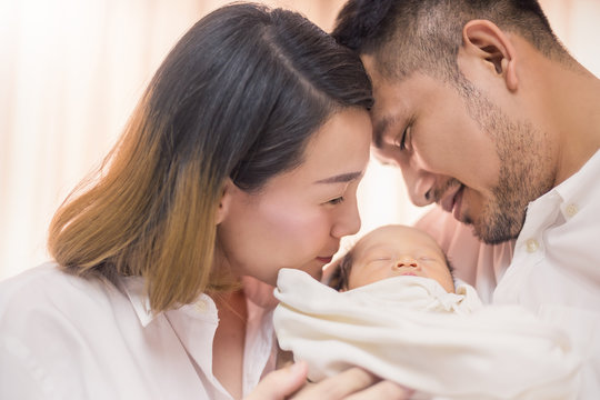 Asian parents newborn baby, Close up portrait of asian young couple father mother holding kissing their new born baby in hospital bed. Happy family love newborn nursery mother’s day holiday concept