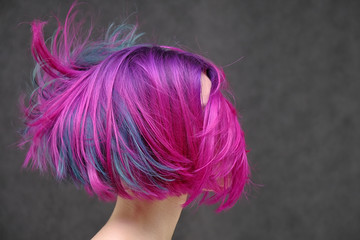 Concept Portrait of a punk girl, young woman with chic purple hair color in studio close up on a colorful background with fluttering hair.