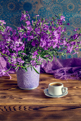 The bouquet of plant (Matthiola farinosa) and cup of coffee close-up