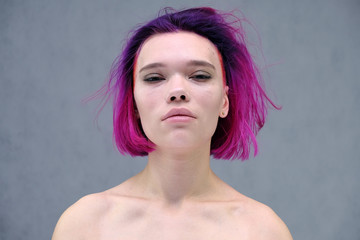 Concept Portrait of a punk girl, young woman with chic purple hair color in studio close up on a colorful background with fluttering hair.