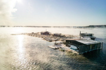 Aerial shot of the floating fish farm at the steaming lake in the Russia