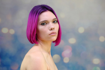 Concept Portrait of a punk girl, young woman with chic purple hair color in studio close up on a colorful background with fluttering hair.