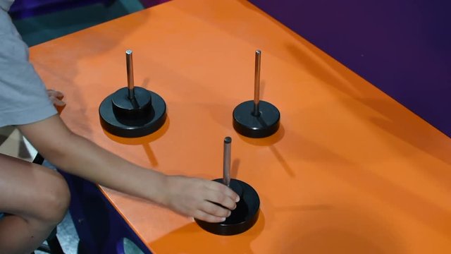 Child completing a Hanoi circle puzzle moving circular discs between three rods demonstrating critical thinking and problem solving. 