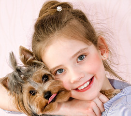 Adorable smiling little girl child holding and playing with puppy yorkshire terrier