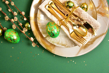 Table setting in easter style. Mimosa, painted green eggs, golden cutlery.