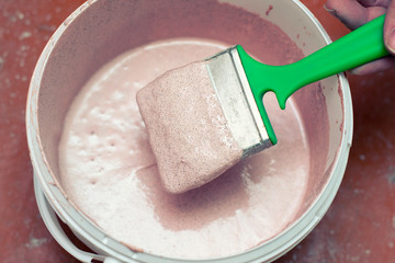 A bucket of primer with a paintbrush. Preparation of the wall for painting.