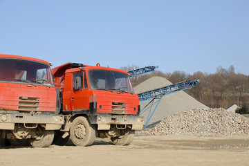 Fototapeta na wymiar Tatra's red dump truck in the background of rubble sorting. Elements of equipment for the extraction and sorting of rubble. Production of construction materials. Metal construction for working