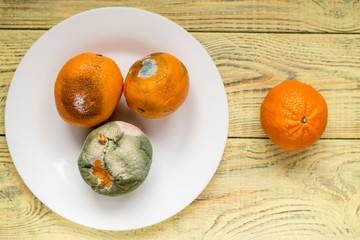 Rotten and fresh orange on wooden background.