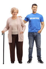 Young male volunteer helping an elderly woman with a walking cane