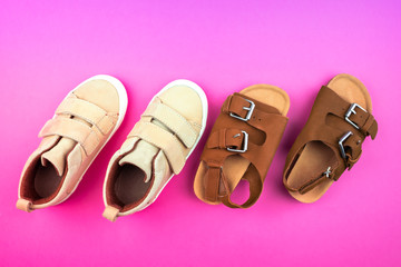 Sneakers and sandals on a trendy pink color background, top view, summer shoes.