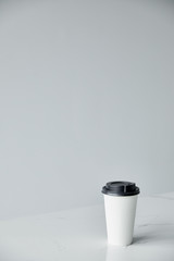 white disposable cup with black cap isolated on grey with copy space