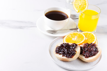 Concept of tasty breakfast.Fresh baked bun with sweet jam, orange juice and cup of coffee.Great start to your day