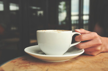 female hand holding hot coffee cup