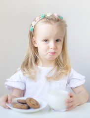 Little blond girl drink a glass of milk with different emotions, indoor, healthy food concept