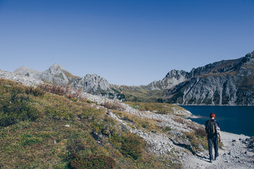 Fototapeta na wymiar Wanderer mitten in der Bergen an einem Bergsee im Rätikon.