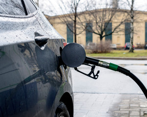 Selective focus the green fuel injector pumps gasoline into the car at the pump filling station.