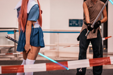 Young cos player girl learning how to use a light sabre sward. Comic and animation event, costume and play concept. 