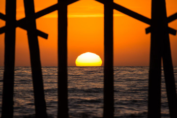 Ocean pier silhouette during orange sunset west coast