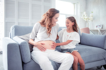 Obraz premium Daughter feeling happy thinking about her future younger brother