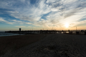 Obraz premium Sunset over an ocean pier on the west coast