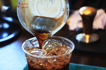 pouring coffee on the ice into glass.