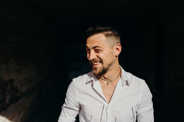 A young man in white shirt laughing happily outdoor. Street fashion.