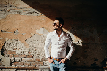 Portrait of handsome happy young businessman. Man dressed in white shirt and sunglasses laughing happily on the grunge background