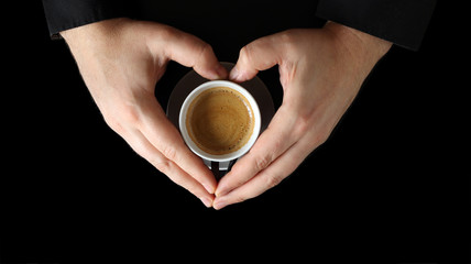 Male hand holding a coffee cup. Close up of a hand of man holding a warm mug with fresh coffee isolated on black background. Coffee concept
