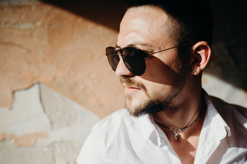 Obraz premium Portrait close up of handsome young businessman. Man dressed in white shirt and sunglasses on the grunge background
