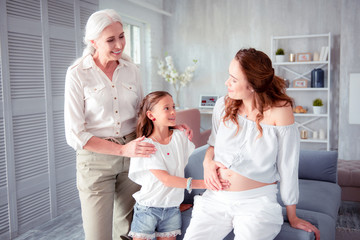 Grey-haired elderly woman looking at her pregnant daughter