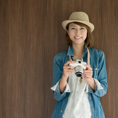 ミラーレス一眼カメラを持ち微笑む女性