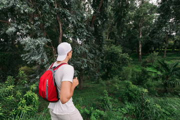Traveler man with backpack walking in the forest