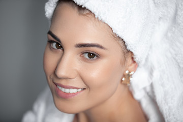 Attractive girl wearing white towel on head and white bath robe, smiling