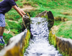 clear spring water descends towards the valley with a young boy