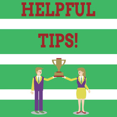 Writing note showing Helpful Tips. Business concept for advices given to be helpful knowledge in life Man and Woman Business Suit Holding Championship Trophy Cup