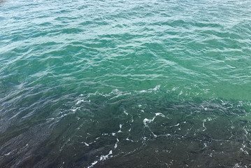 Panorama of a small ripple on the azure surface of the Black Sea, endlessly stretching to the horizon under the cloudy spring sky.