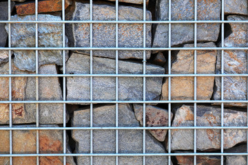 Zaun mit Gabionen und Steinen