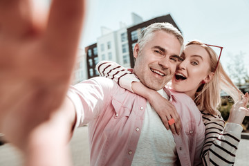 Delighted positive blonde woman touching her hair