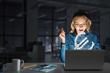 Attractive blonde wearing glasses in dark office using laptop. Mixed media