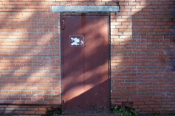 Brick wall with destruction, with rusty iron door. City background