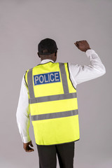 Salisbury, Wiltshire, UK, April 2019. Rear view of a police officer in reflective jacket and right arm raised.