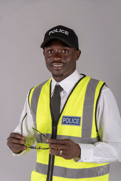 Salisbury, Wiltshire, UK. April 2019. Portrait of a smiling police officer in uniform and holding a pair of dark glasses.