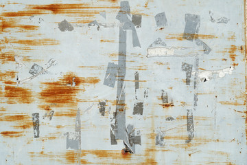Rusty scratches and marks from labels and stickers on grey painted metal wall