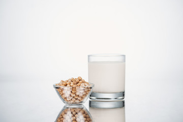 chickpea vegan milk in glass near bowl with beans on grey background