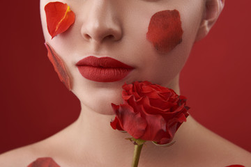 Woman with red lips having fresh rose touching her chin