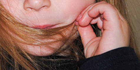 Manos de niña con el pelo en la boca 