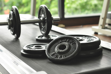 Plakat dumbbell and barbell on floor at gym