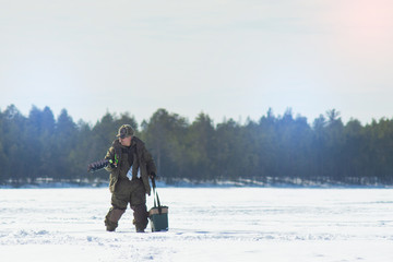 Fototapeta na wymiar a man on a winter fishing drill hole ice drill