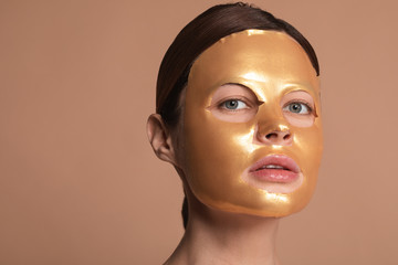 Calm woman having golden sheet mask on the face