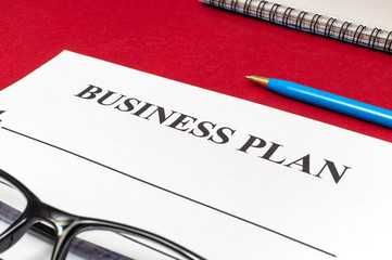 Strategy business plan with pen, glasses and money on red table.